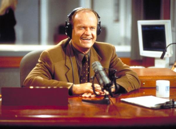 Kelsey Grammer as Frasier Crane in Frasier, sat in front of a radio microphone at a wooden desk